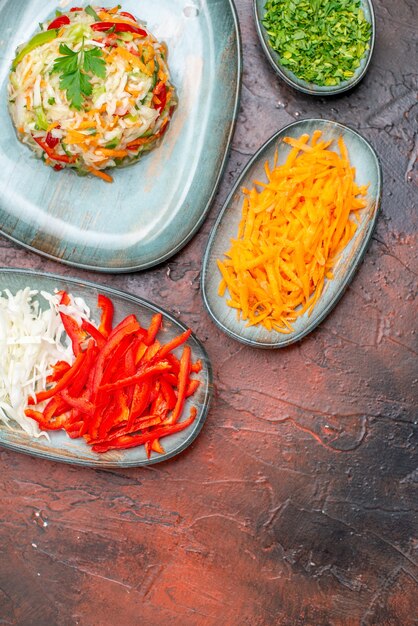 Ensalada de verduras vista superior con repollo de zanahoria en rodajas y pimientos en una mesa oscura