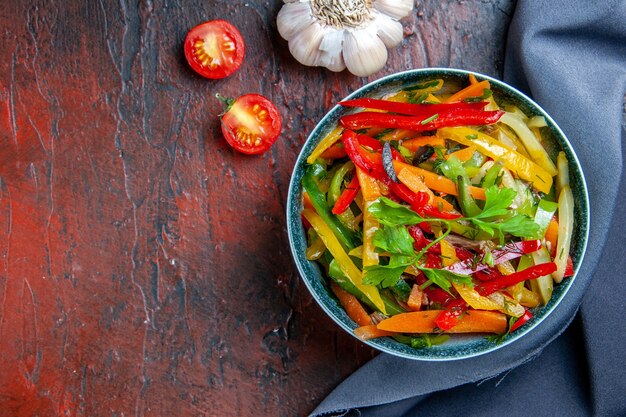 Ensalada de verduras de vista superior en un tazón de ajo chal azul ultramarino en lugar libre de mesa rojo oscuro