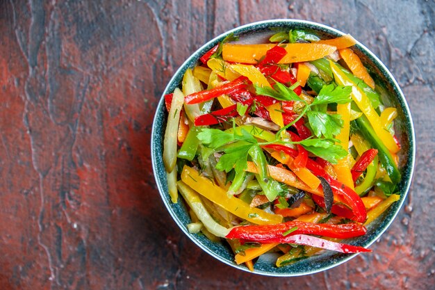 Ensalada de verduras vista superior en un tazón en la mesa de color rojo oscuro