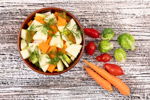 Ensalada de verduras con zanahoria y rábano en un tazón de cerámica en la mesa de madera blanca