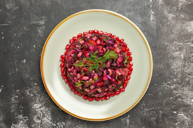 Ensalada de vinagreta de vista superior con granadas y frijoles en superficie gris