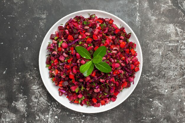 Ensalada de vista superior cercana con vegetales rojos en un plato blanco sobre fondo gris