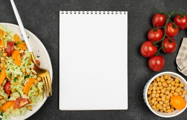 Ensalada de vista superior con garbanzos y tomates con bloc de notas en blanco