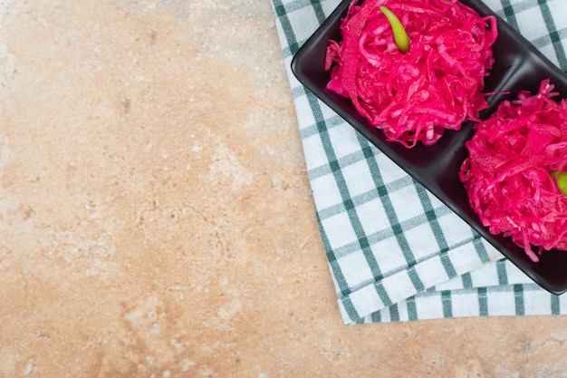 Ensaladas de chucrut rojo sobre placa negra con mantel