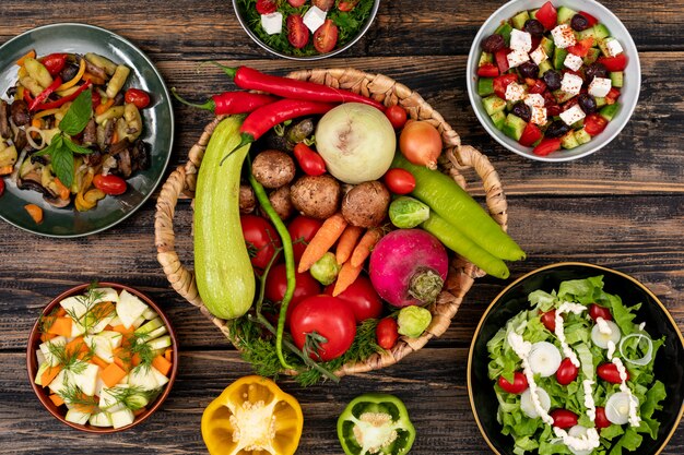 Ensaladas de verduras en concepto de vista superior de la mesa de madera