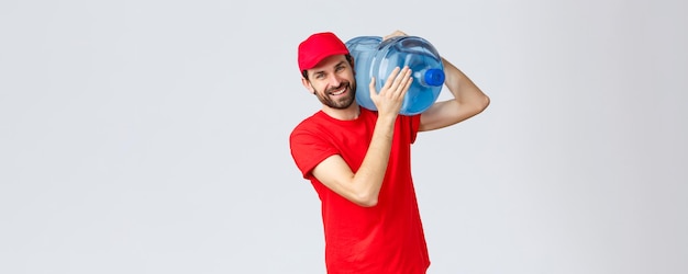 Entrega de alimentos y comestibles para llevar Concepto de pedidos sin contacto covid19 Mensajero amigable con uniforme rojo que lleva agua embotellada al hombro a su oficina o casa sonriendo alegre