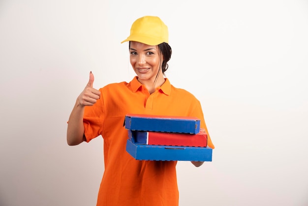 Entrega feliz mujer sosteniendo pizza y haciendo pulgares.