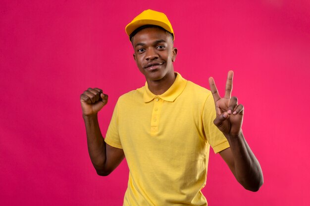 Entrega hombre afroamericano en polo amarillo y gorra levantando el puño mostrando el signo de la victoria con los dedos en rosa