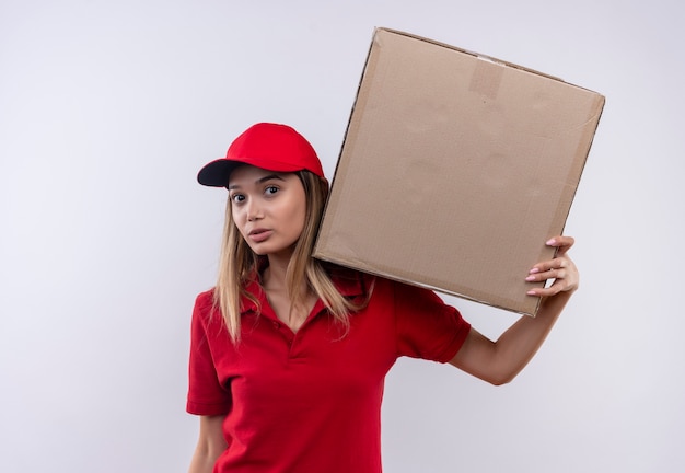 Entrega joven mujer vistiendo uniforme rojo y gorra sosteniendo una caja grande en el hombro