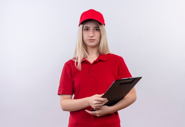 Entrega joven vistiendo camiseta roja y gorra sosteniendo el portapapeles en la pared blanca aislada