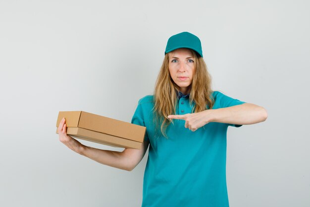 Entrega mujer apuntando a caja de cartón en camiseta, gorra