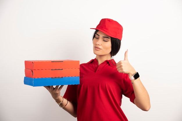 Foto gratuita entrega mujer sosteniendo pizza sobre fondo blanco dando pulgares arriba gesto.