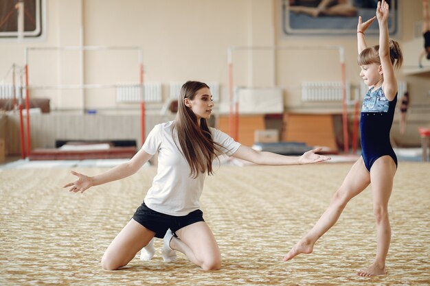 Entrenador con alumno. Chicas gimnastas, realiza diversos ejercicios gimnásticos y saltos. Niños y deporte, un estilo de vida saludable.