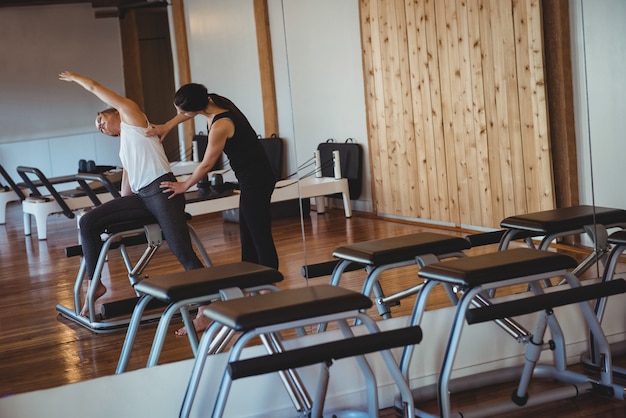 Entrenador ayudando a una mujer mientras practica pilates