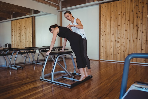 Entrenador ayudando a una mujer mientras practica pilates