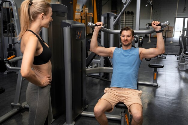 Entrenador ayudando a principiantes en el gimnasio.