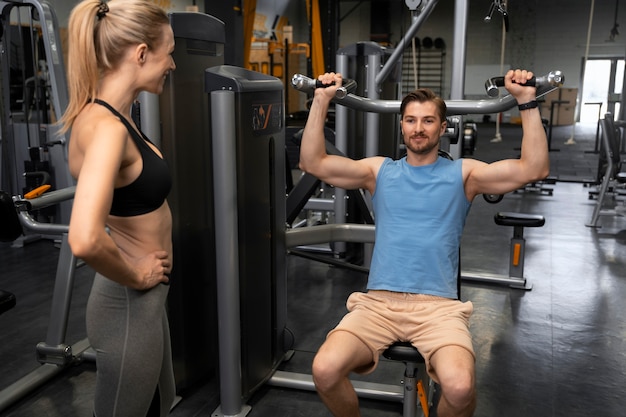 Entrenador ayudando a principiantes en el gimnasio.