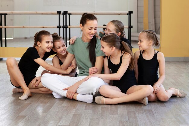 Entrenador de ballet femenino posando con chicas en el gimnasio
