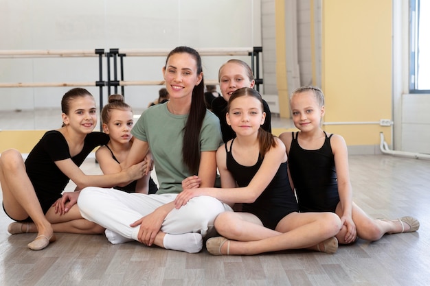 Entrenador de ballet femenino posando con chicas en el gimnasio