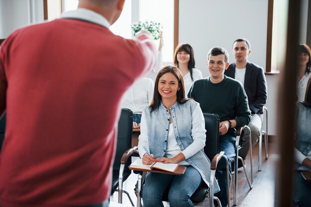 Entrenador divertido. Grupo de personas en conferencia de negocios en el aula moderna durante el día