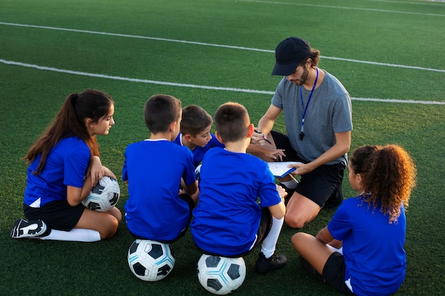 Entrenador de fútbol de alto ángulo enseñando a los niños