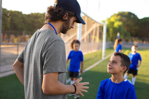 Entrenador de fútbol ayudando a niños de tiro medio