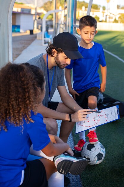 Entrenador de fútbol enseñando a los niños vista lateral