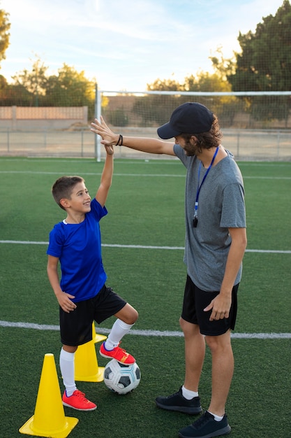 Foto gratuita entrenador de fútbol felicitando a la vista lateral del niño