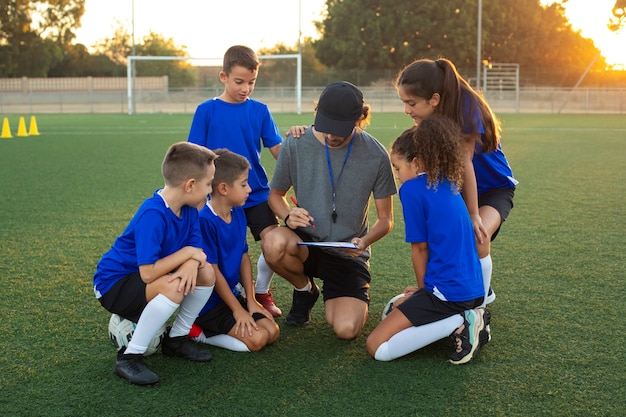 Foto gratuita entrenador de fútbol de vista frontal enseñando a los niños