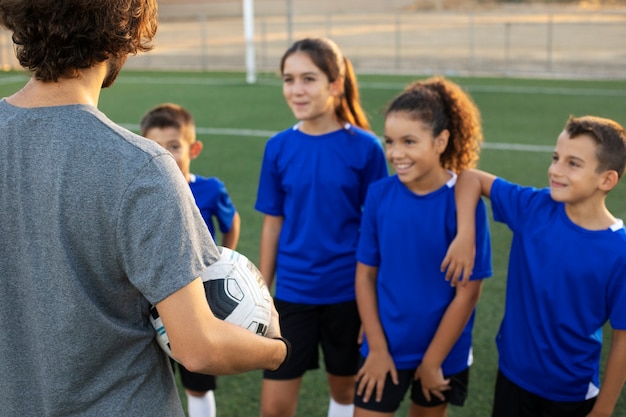 Entrenador de fútbol de vista lateral hablando con niños