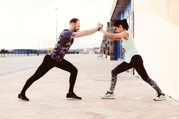 Entrenador masculino ayudar a la atleta femenina al hacer ejercicio de estiramiento