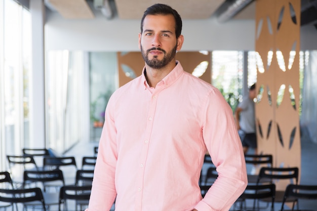 Entrenador de negocios seguro positivo posando en la sala de entrenamiento