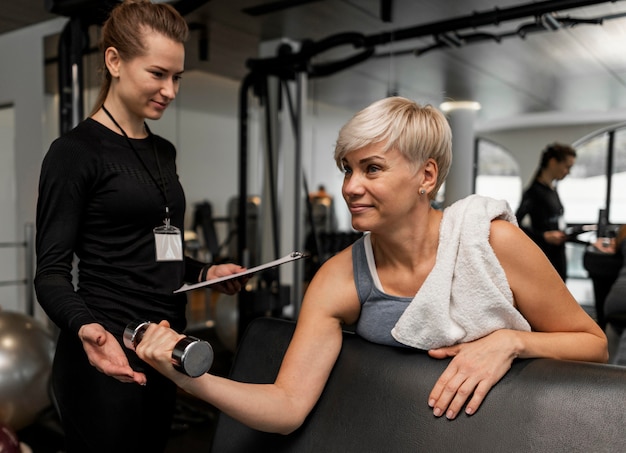 Entrenador personal femenino y su cliente con mancuernas