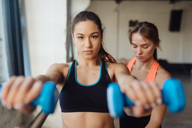 Entrenador personal joven ayudando con entrenamiento en el gimnasio. Mujer, hacer, ejercicios