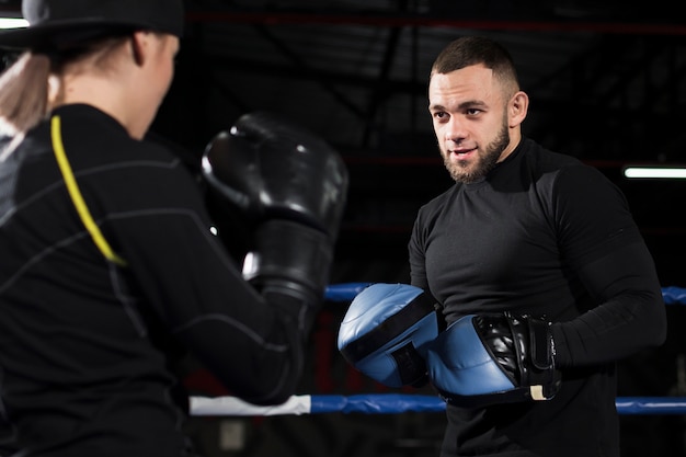 Entrenador practicando con boxeadora en guantes protectores