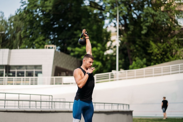 Entrenamiento de chico deportivo con pesas rusas. Foto de hombre guapo con buen físico. Fuerza y motivación.