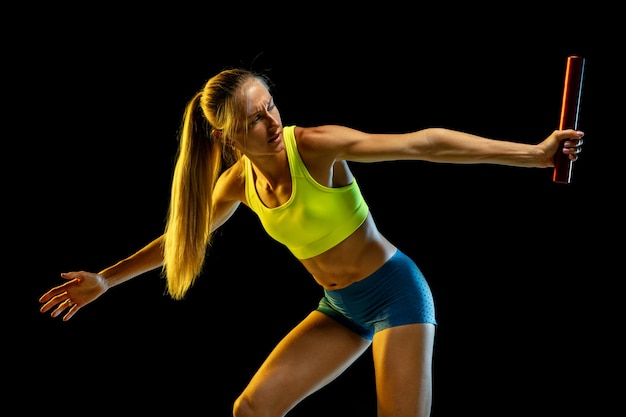 Entrenamiento de corredor de relevos femenino profesional en estudio negro