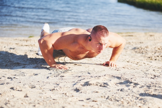 Entrenamiento de fitness hombre empuja hacia arriba. Deporte, ejercicio, fitness, entrenamiento. Estilo de vida saludable. amanecer temprano en la mañana retroiluminado