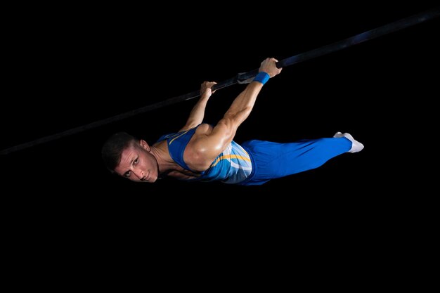 Entrenamiento de gimnasta masculino muscular en gimnasio, flexible y activo. Caucásico ajuste chico ropa deportiva azul