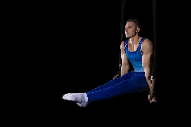 Entrenamiento de gimnasta masculino muscular en gimnasio, flexible y activo. Caucásico ajuste chico ropa deportiva azul