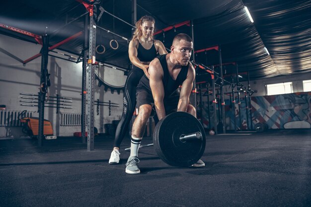 Entrenamiento de la joven pareja deportiva caucásica en el gimnasio juntos