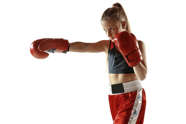 Entrenamiento de luchador de kickboxing femenino joven aislado en la pared blanca. Chica rubia caucásica en ropa deportiva roja practicando artes marciales. Concepto de deporte, estilo de vida saludable, movimiento, acción, juventud.