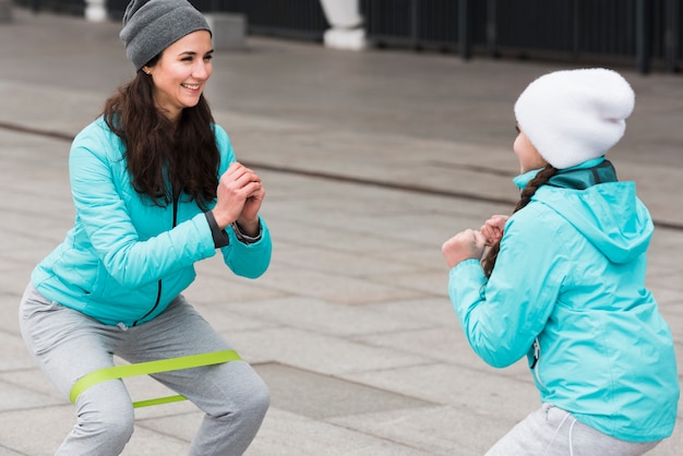 Foto gratuita entrenamiento de mamá y niña de alto ángulo con banda elástica