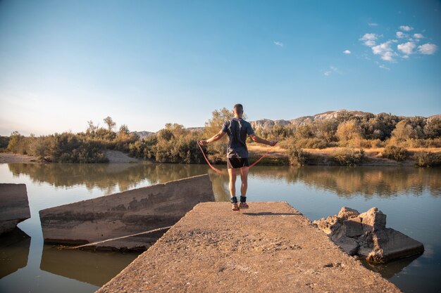 Entrenamiento masculino con una cuerda para saltar junto al río.