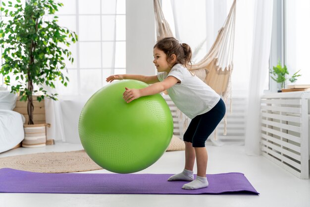 Entrenamiento de niños con tiro completo de pelota de gimnasio