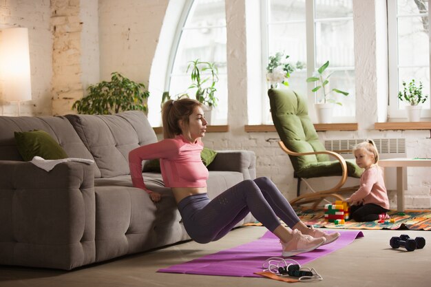 Entrenamiento con sofá. Mujer joven trabajando en casa