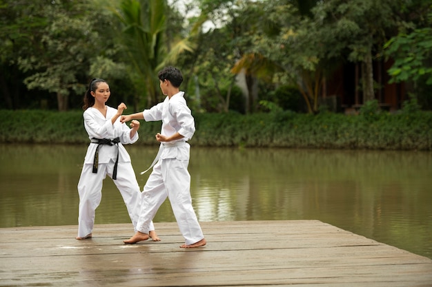 Foto gratuita entrenamiento de taekwondo al aire libre en la naturaleza con dos personas