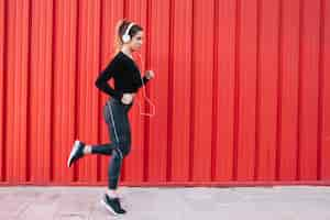 Foto gratuita entrenando a mujer en auriculares en la calle