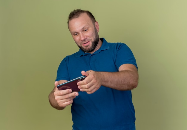 Entretenido hombre eslavo adulto jugando en el teléfono móvil