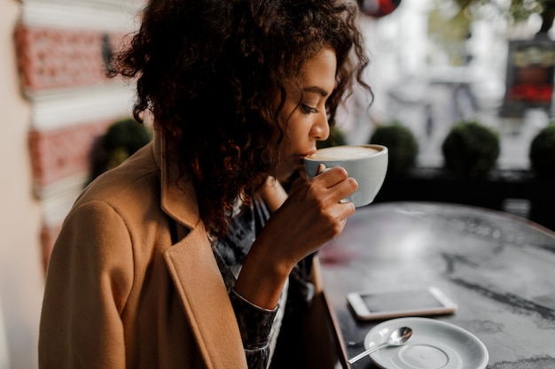 Entusiasta mujer inconformista de piel oscura con peinado afro revisando sus noticias